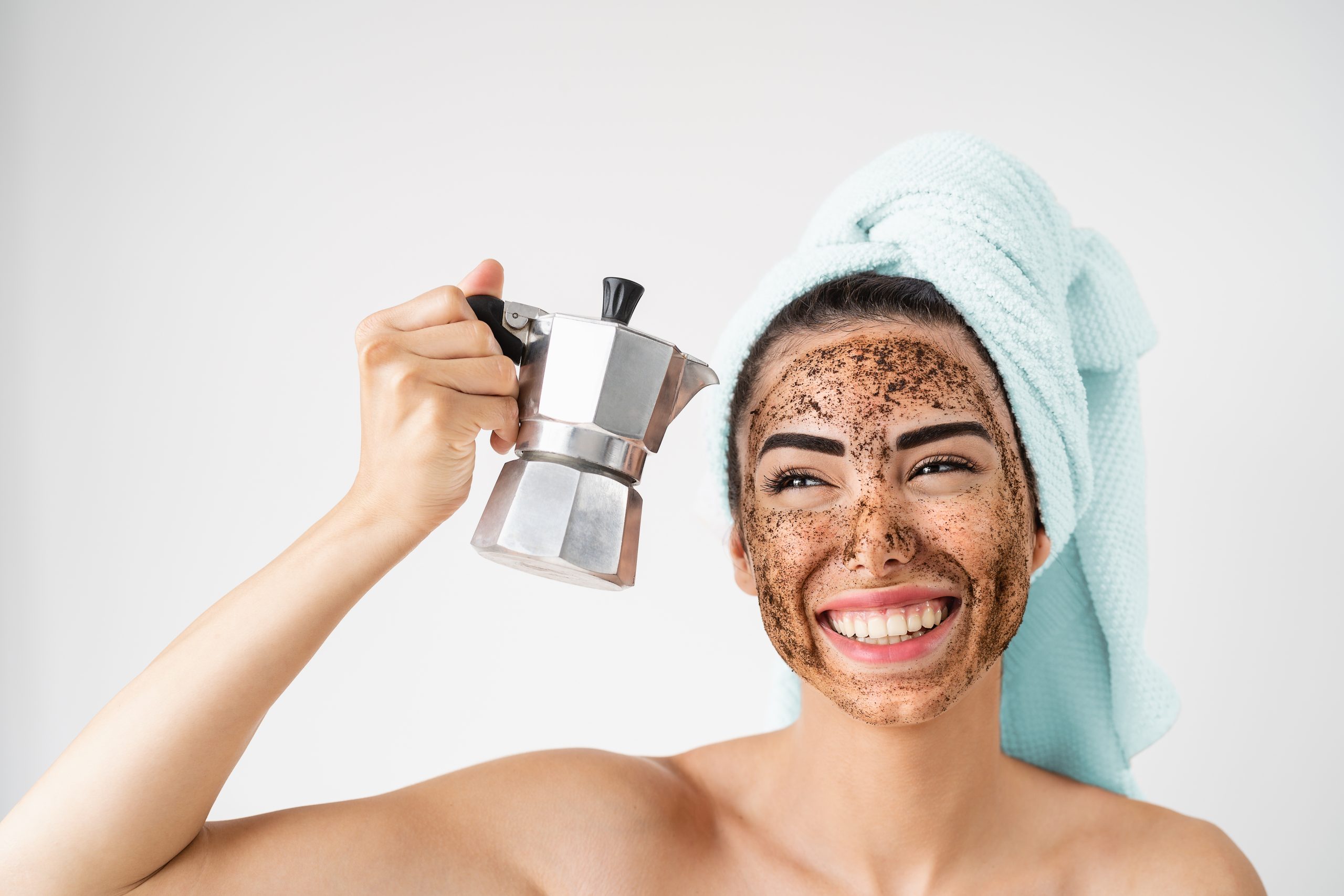 Young smiling woman applying coffee scrub mask on face - Happy girl having healthy skin care spa day at home - Alternative natural exfoliation treatment and people lifestyle concept