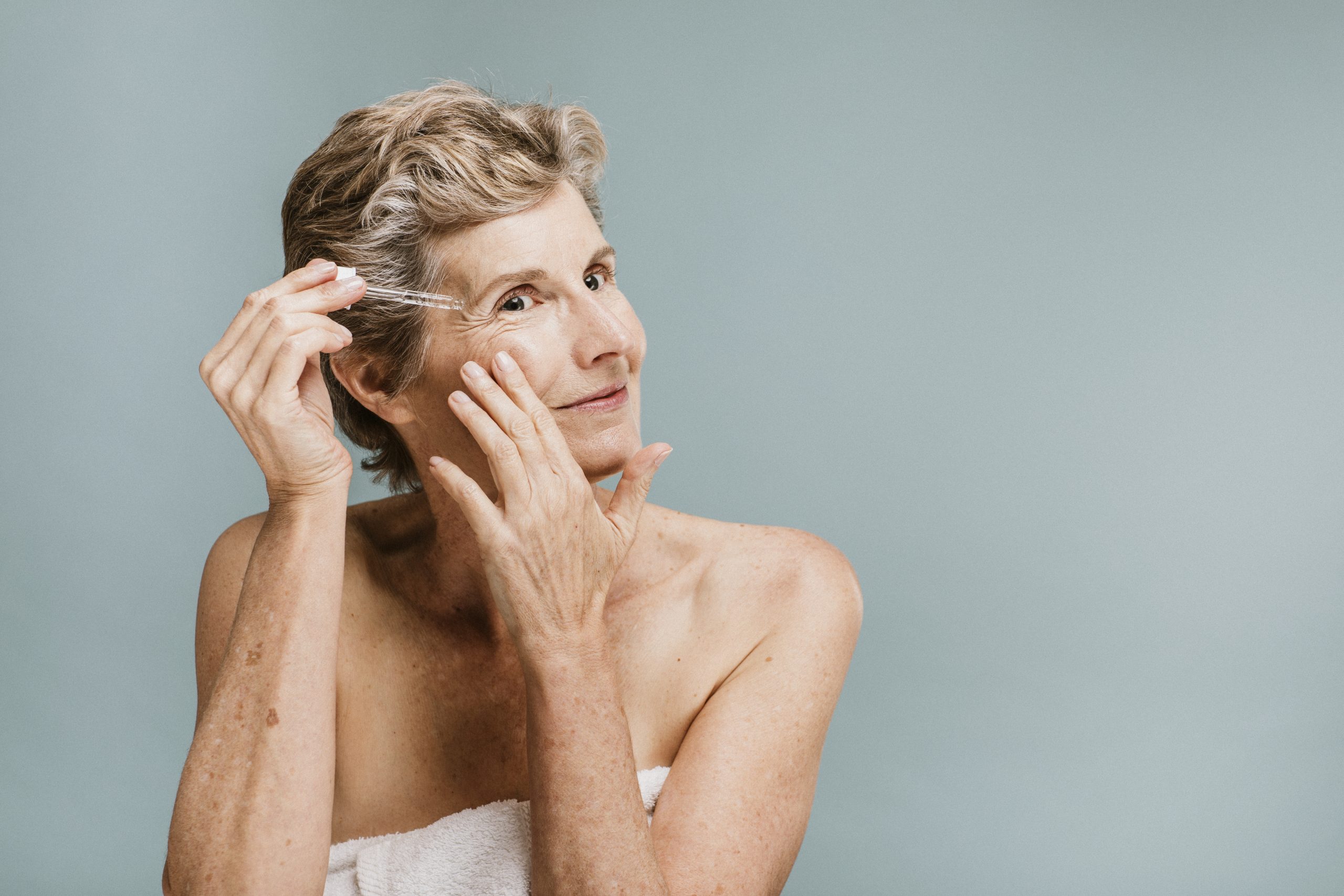 Senior woman applying moisturizer on her eye wrinkles