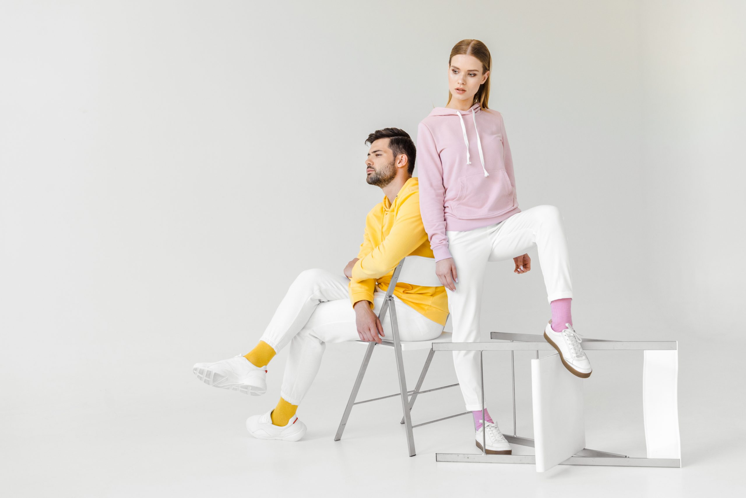 young male and female models in pink and yellow hoodies on white