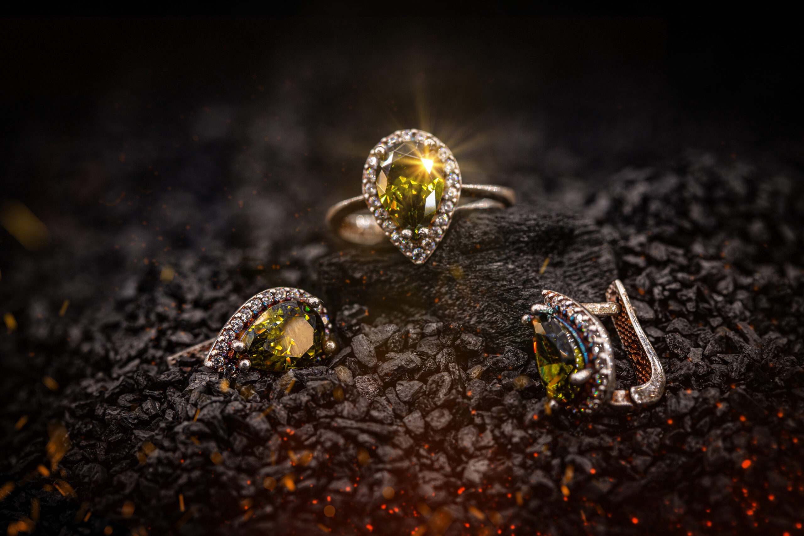 Jewelry ring and earrings witht big yellow gems on black coal background