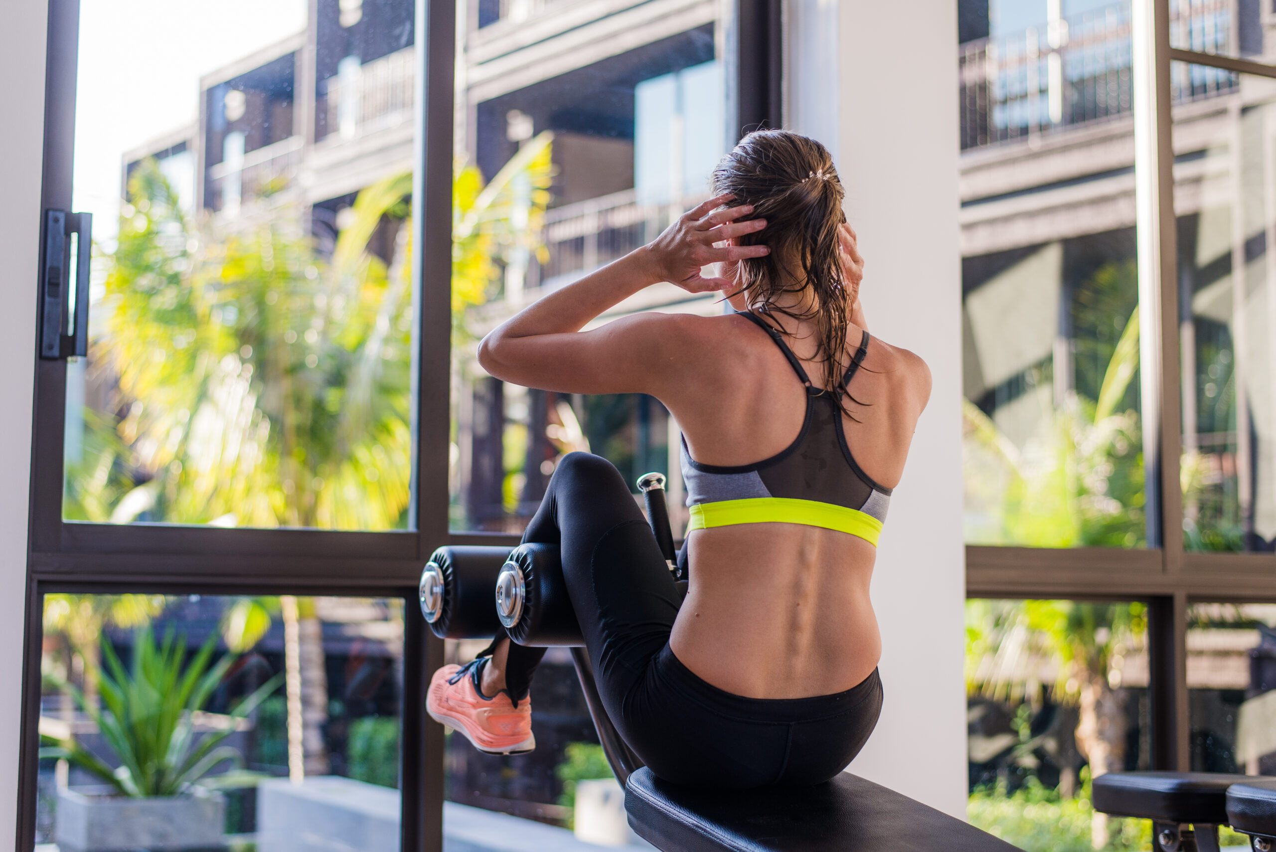 portrait of an athletic woman doing exercising abdominals work-out lying in gym at luxury hotel at summer.