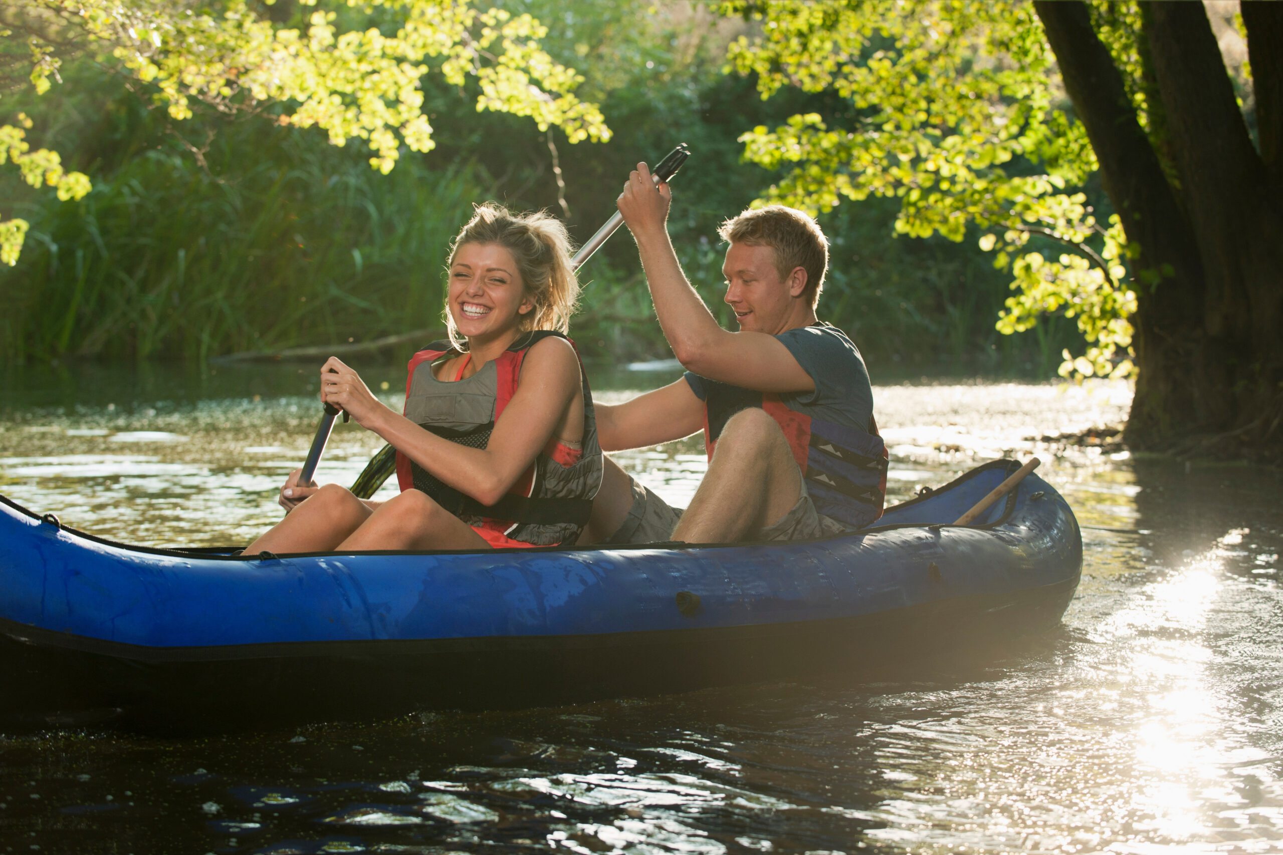 Smiling couple kayaking in creek