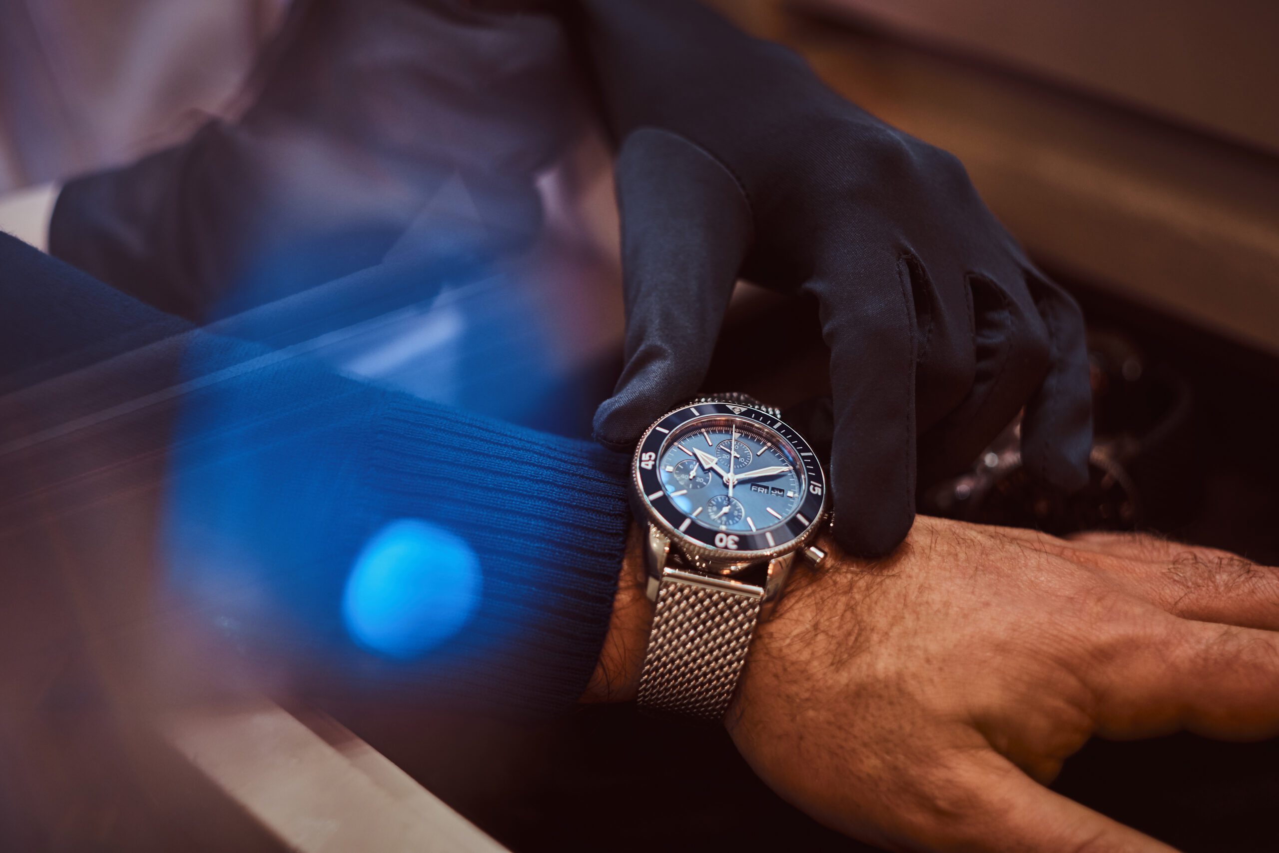 Close-up hands. Assistant helps the client to try on exclusive men's watches.