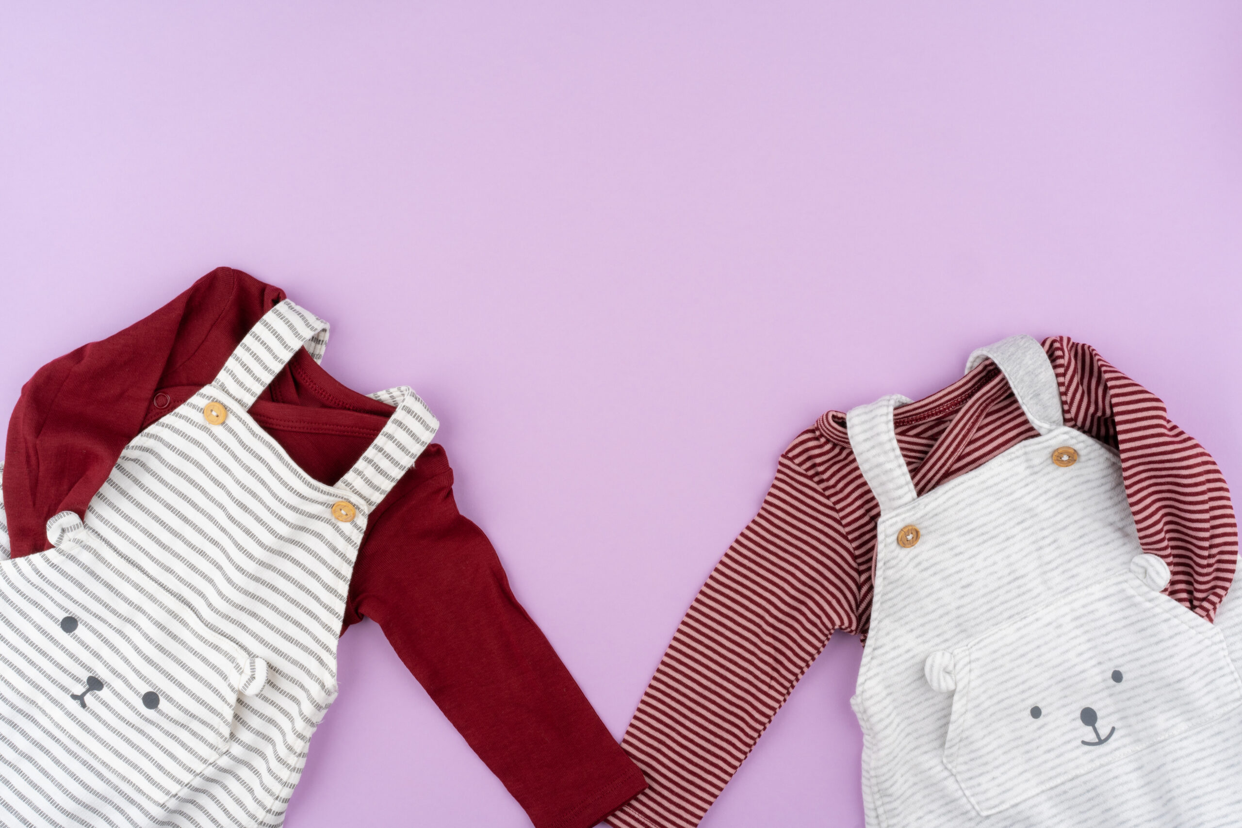 Baby girl clothes on lilac pastel background