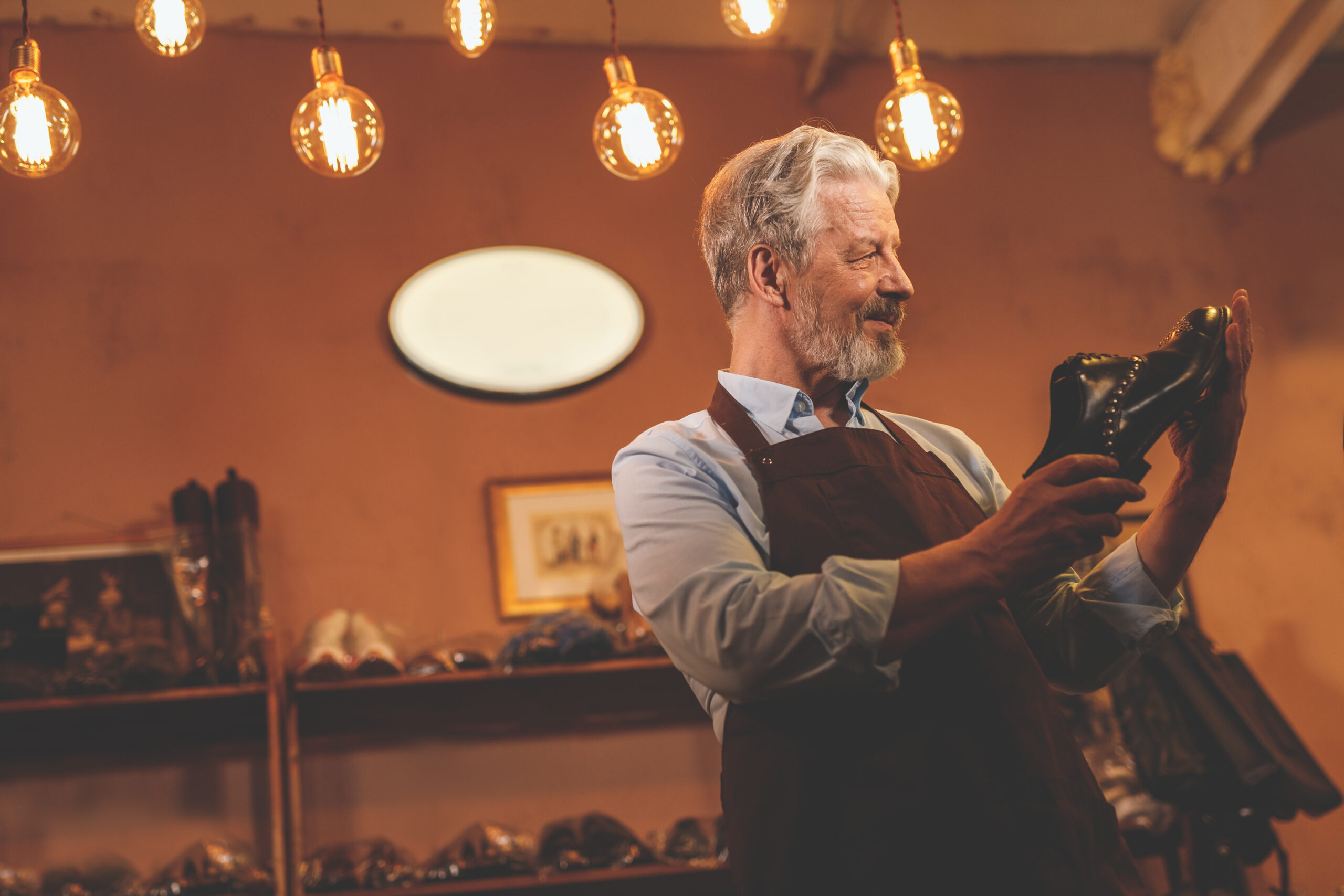 An elderly shoemaker with a shoe in the workshop