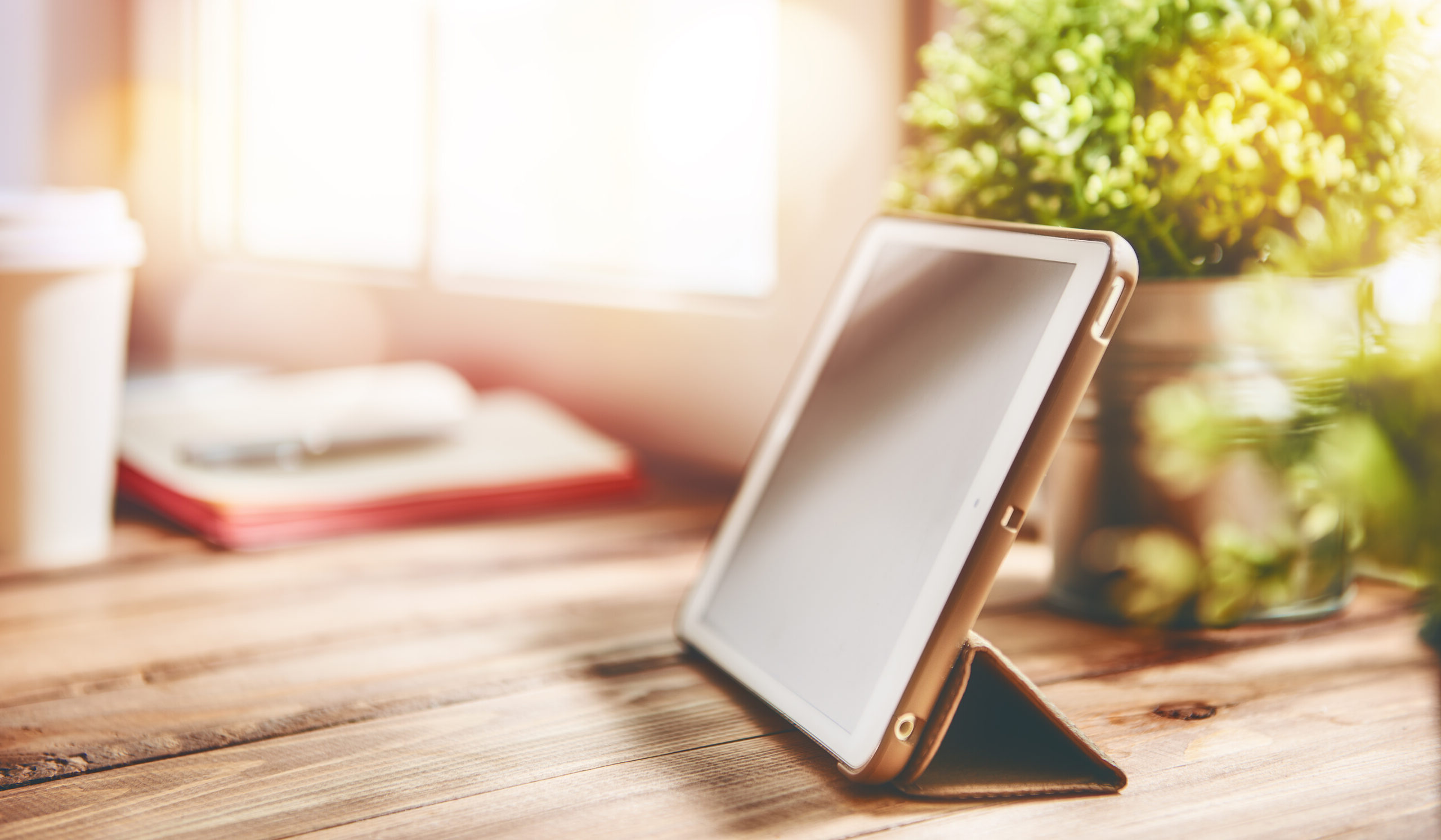 Office workplace with tablet on wood table near the window.