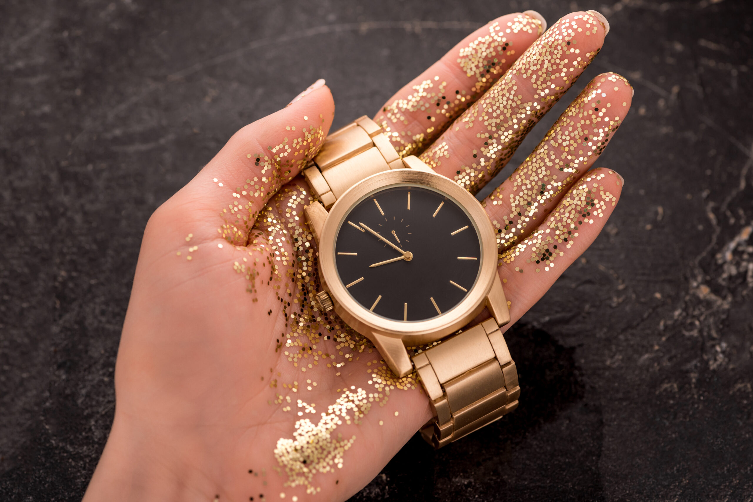 cropped view of golden wristwatch in hand of woman